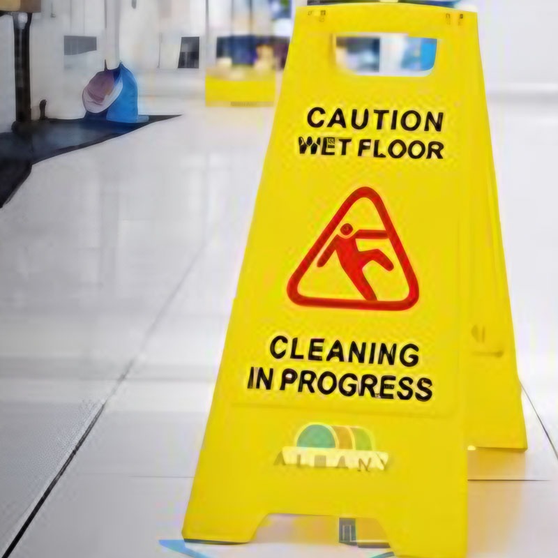 A yellow caution sign warning of a wet floor, placed on the ground to alert people to potential slipping hazards