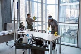 Two individuals focus on their tasks in a spacious office filled with natural light from large windows