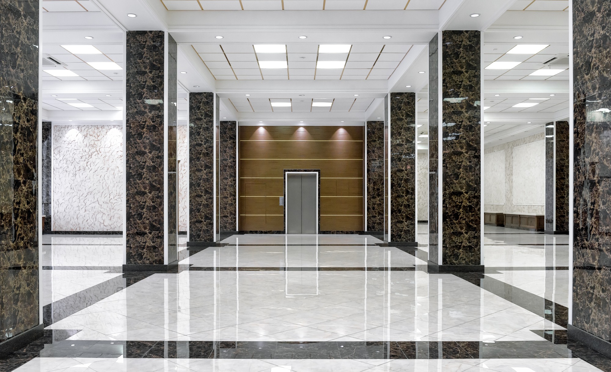A spacious marble hallway featuring white walls and elegant black and white marble flooring